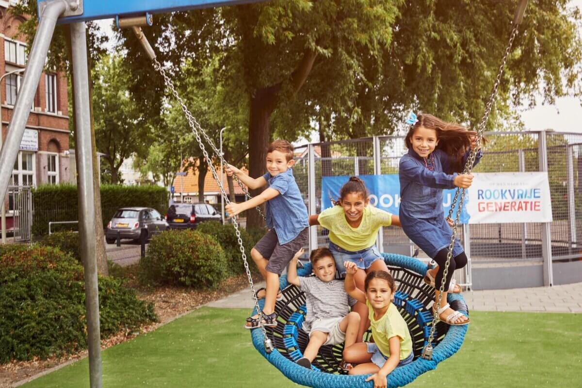 5 kinderen spelen op een schommel in een rookvrije speeltuin