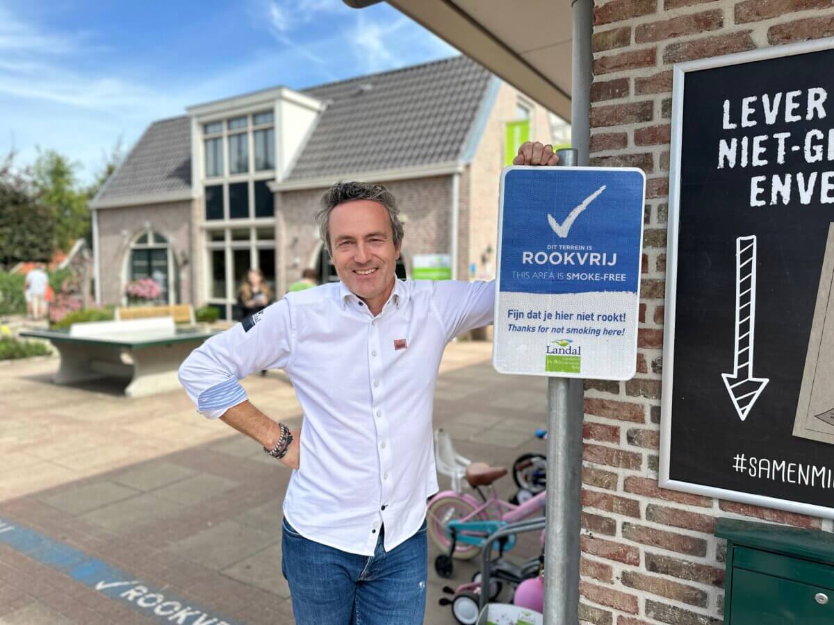 Parkmanager Sander staat naast het rookvrij-bord voor de receptie van het Landal park